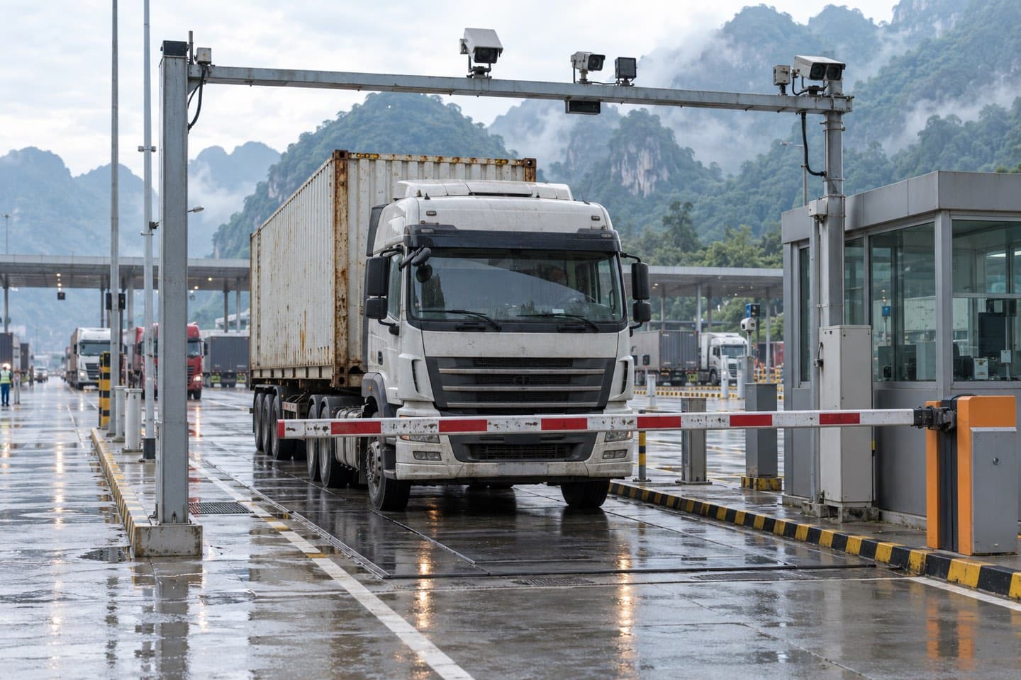 Xe container dừng trước barie điện tử, phía trên là giá gắn camera giám sát tại một cửa khẩu đường bộ